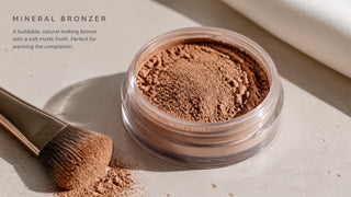 Mineral bronzer powder in an open jar with a soft angled brush