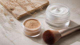 Loose mineral powder and a soft brush beside a jar of hydrating moisturizer for mature skin prep